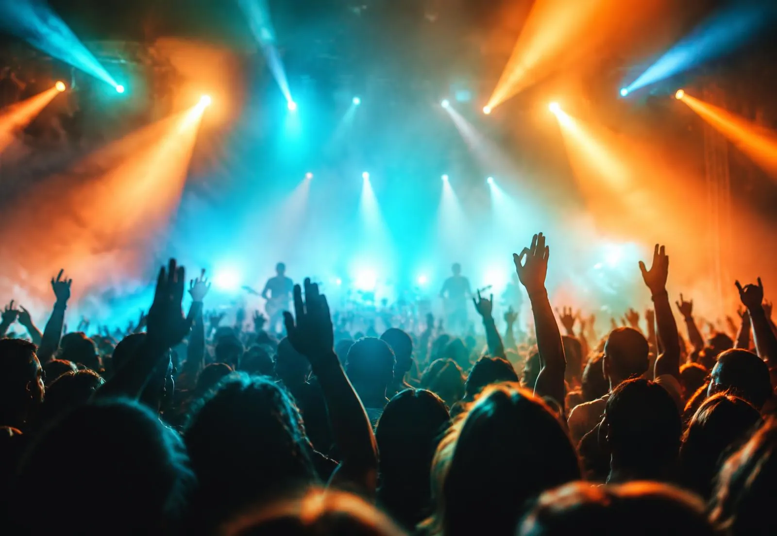 Concert crowd with raised hands under stage lights